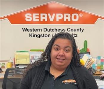 A photo of a smiling female SERVPRO employee with long black hair in a black SERVPRO sweater