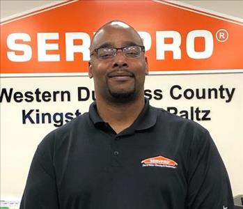 A photo of a smiling male SERVPRO employee wearing a black polo shirt