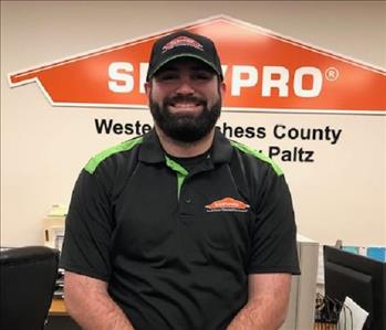 A profile photo of a smiling male employee in a black shirt with the SERVPRO logo on the upper corner