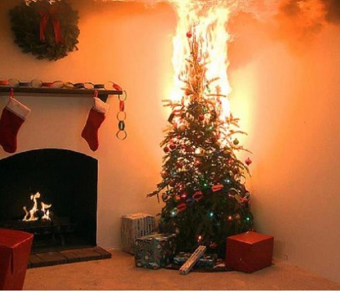 A Christmas tree on fire in front of a fireplace in a home