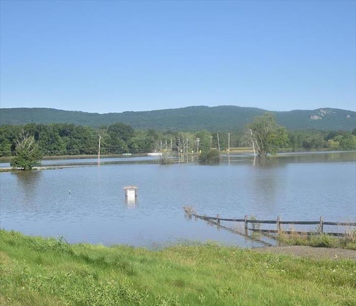 A large green field on a farm, flooded by more than a foot of water.