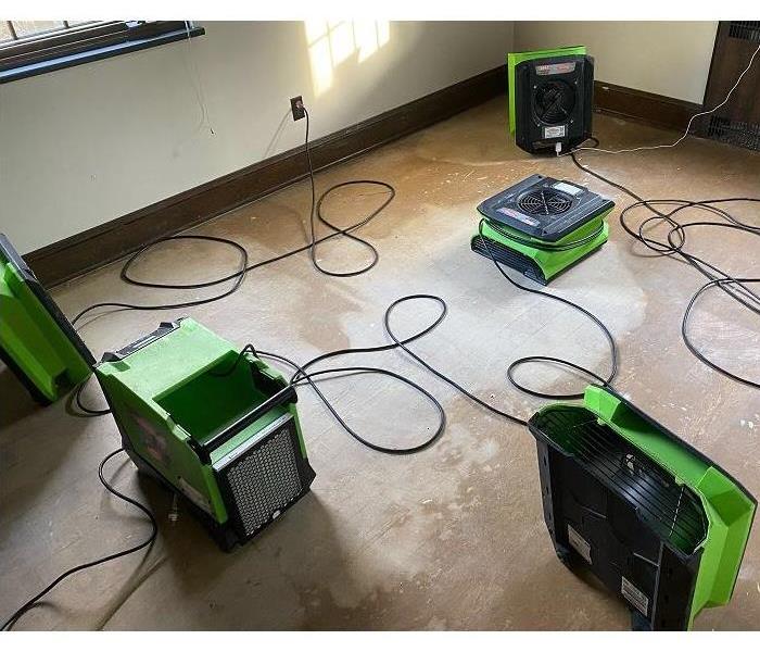 Several pieces of SERVPRO drying equipment placed throughout a room to dry it out from water damage.