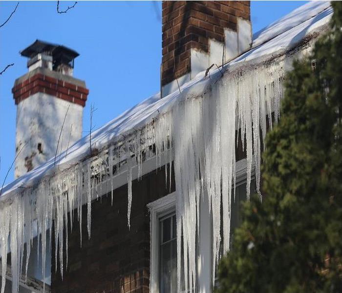 Icicles, snow and ice build-up on the roof and gutters of a home