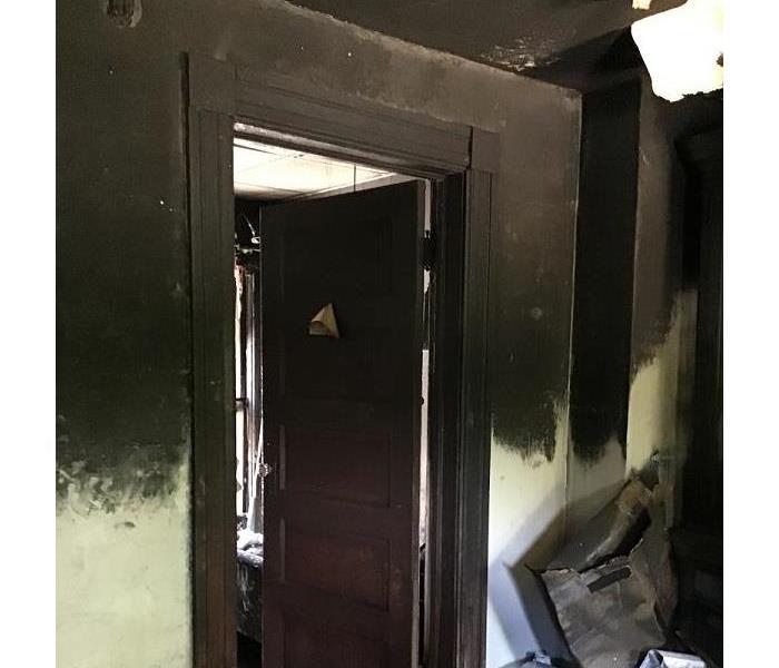 An interior room with almost black walls after being heavily covered by smoke and soot.