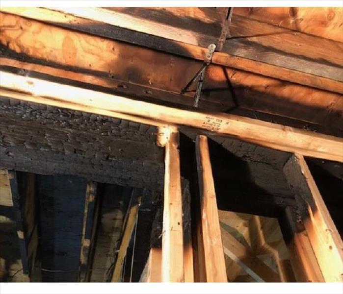 An image showing the rafters of a basement ceiling burned, charred and scorched.